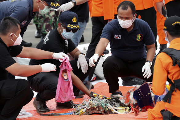 Investigators sort debris found on the waters off Java Island around where a Sriwijaya Air passenger jet crashed, at Tanjung Priok Port in Jakarta, Indonesia.