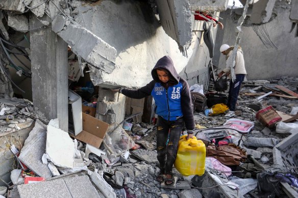 People inspect damage and recover items in Rafah following Israeli air strikes on March 26.