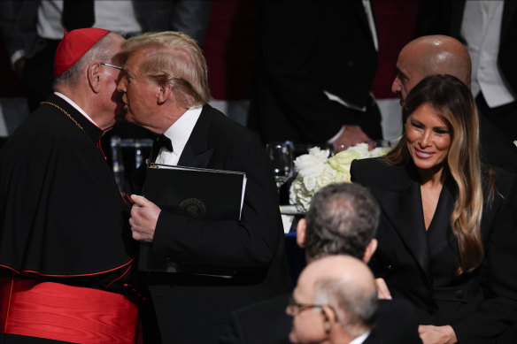 Trump talks to Cardinal Dolan as former first lady Melania Trump watches on.