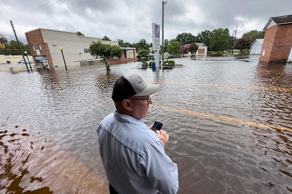 Randy Sikes speaks to his relatives on a mobile phone as he stands in residual rain water flooding the downtown area caused by Tropical Storm Debby, in Bladenboro, North Carolina.