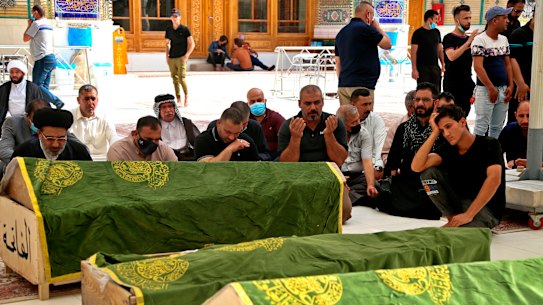 Mourners pray near the coffins of coronavirus patients who were killed in a hospital fire, in Najaf, Iraq.