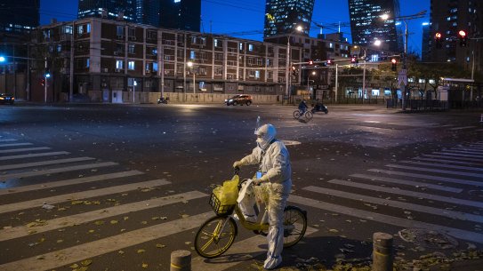 An epidemic control worker who performs nucleic acid tests on people  stops to check a list on a usually busy street during rush hour on Friday.