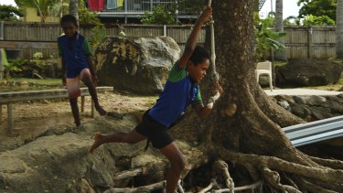 Dereece Cook swings on a rope tied to a tree at his home on the foreshore of Thursday Island watched by his brother Traquiin Cook.