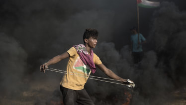A Palestinian protester hurls stones at Israeli troops during a protest at the Gaza Strip's border with Israel on Friday.