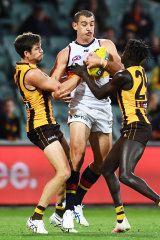 Adelaide's Taylor Walker takes on a pair of Hawks.