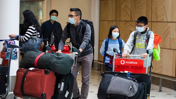 Passengers arrive at Sydney Airport on Monday wearing masks.