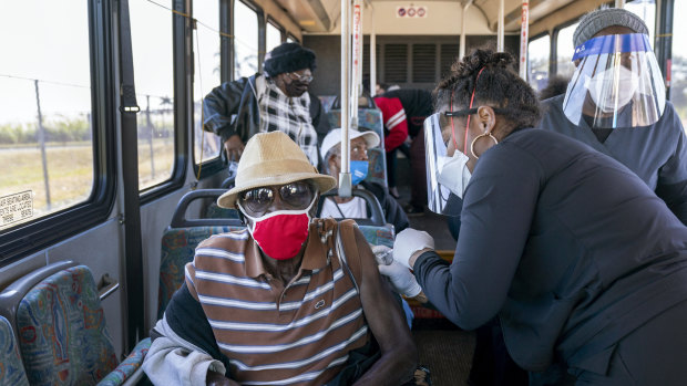 A senior receives a COVID-19 vaccine from a healthcare worker after arriving on a bus to a vaccination site at Anquan Boldin Stadium in Pahokee, Florida. 