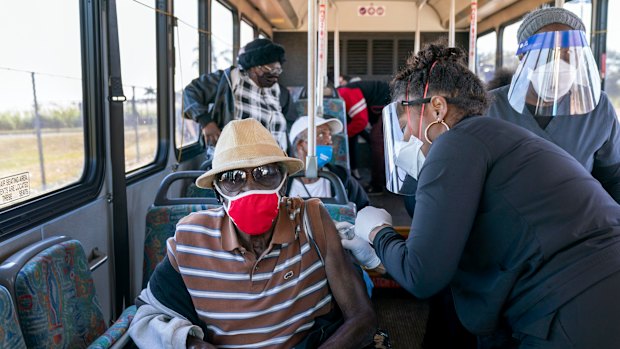 A senior receives a COVID-19 vaccine from a healthcare worker after arriving on a bus to a vaccination site at Anquan Boldin Stadium in Pahokee, Florida. 