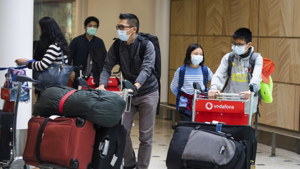 Passengers arrive at Sydney Airport on Monday wearing masks.