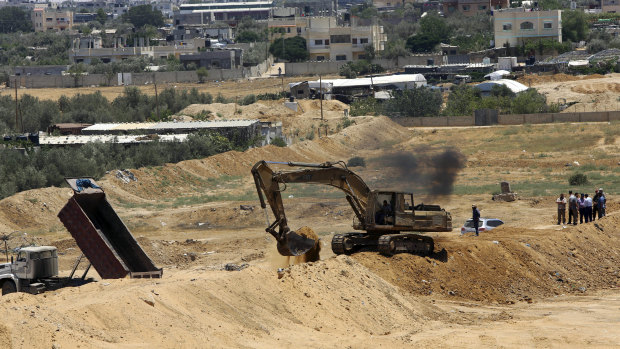 A backhoe removes sand barriers to create a buffer zone near entrances to tunnels in Rafah, along the Egyptian border.