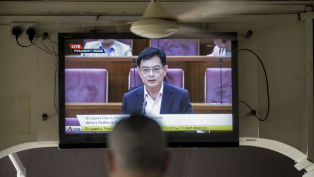 A man watches a television showing Singapore's Deputy Prime Minister Heng Swee Keat annoucing a major new economic stimulus package.