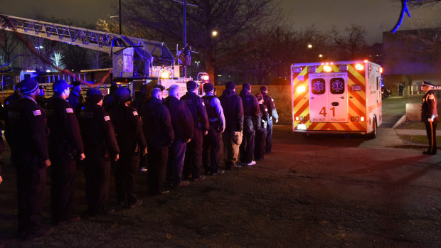 Chicago police officers and firefighters form an honour guard as the body of Chicago police fficer Samuel Jimenez is brought to the coroner.