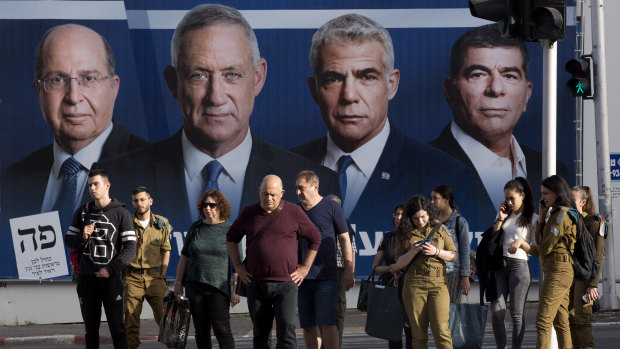 People wait for a green light next to an election campaign billboard showing Blue and White party leaders, from left, Moshe Yaalon, Benny Gantz, Yair Lapid and Gabi Ashkenazi in Ramat Gan, Israel, on Sunday.