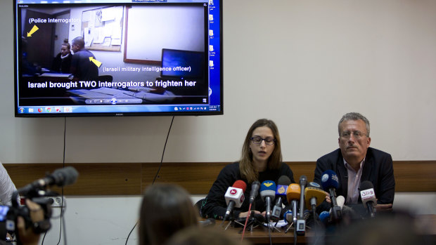 Palestinian Bassem Tamimi, right, sits during a press conference while a video of his daughter's interrogation plays on the screen.