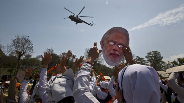A supporter of India's ruling Bharatiya Janata Party (BJP) holds a face mask of Indian Prime Minister Narendra Modi.