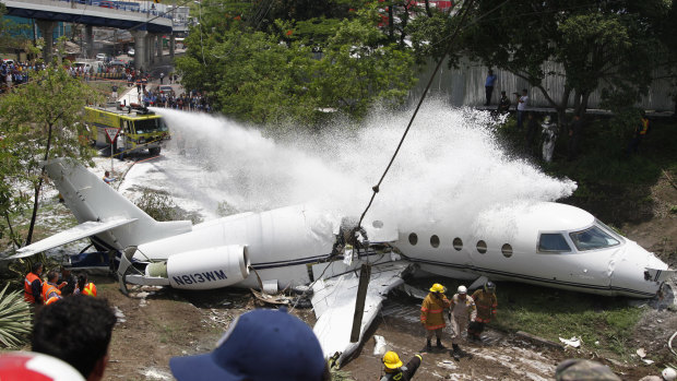 A fire truck sprays foam on the jet that appears broken in half near the centre.