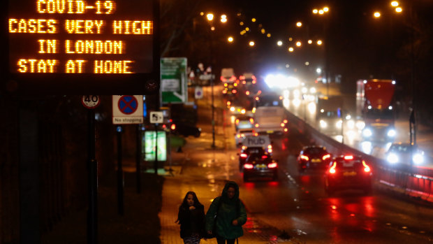 As a new strain takes hold in Britain, a sign near a highway in London urges people to stay at home.