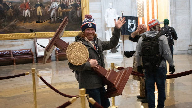 A pro-Trump protester identified as Adam Johnson carries the lectern of Speaker of the House Nancy Pelosi through the US Capitol Rotunda.