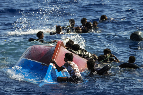 Migrants swim next to their overturned wooden boat during a rescue operation by Spanish NGO Open Arms at south of the Italian Lampedusa island in August.