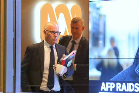 The ABC's executive editor John Lyons is followed by an AFP officer during raids.