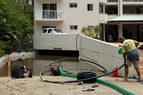 Residents pump water from an apartment complex’s parking garage in Cairns in the wake of Cyclone Jasper.