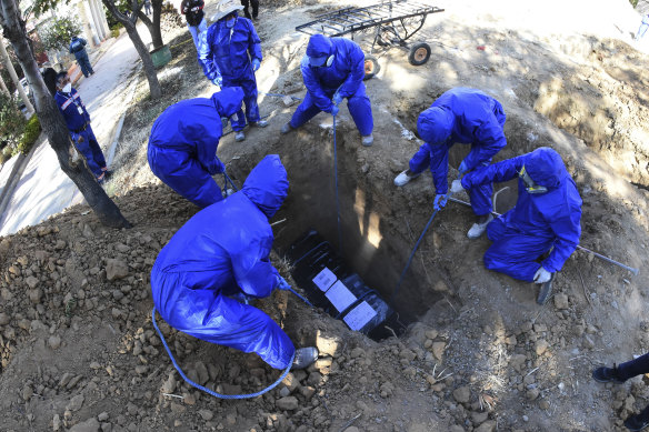 A coffin wrapped in plastic holding the remains of Cristobal Huanca Mendoza is lowered into a common grave at a cemetery in Cochabamba, Bolivia. The coffin is wrapped in plastic as is common by funeral homes when working with COVID-19 victims.