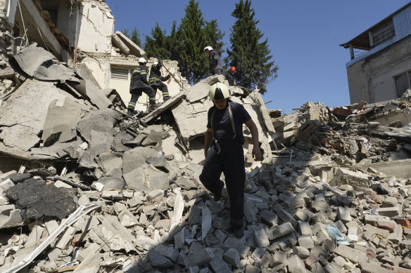 Firefighters dig through the rubble of a school building destroyed by a missile strike in Kharkiv, Ukraine, on Monday.