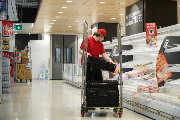 Restocking an empty fridge at a Coles supermarket.