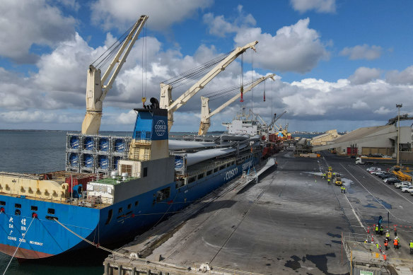 Wind turbine blades are offloaded from a vessel at the port. 