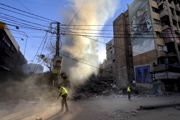 Workers clean a street under a giant portrait of the late Hezbollah military commander Imad Mughniyeh, in Dahiyeh, a southern suburb of Beirut.