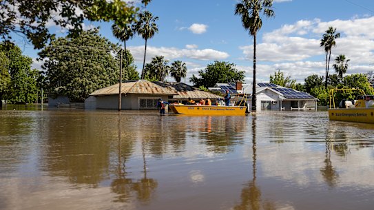 Emergency crews are transported by boat over flooded streets in Forbes. 