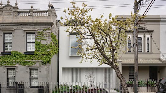 The sleek and minimal contemporary house is framed by two ornate Victorian terraces on either side.