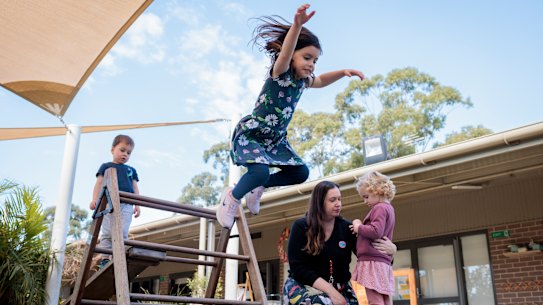 Mila makes a leap with preschool friends Eddy and Olena, and teacher Angela Aldridge, at Goodstart’s Crescent Early Learning Centre. 