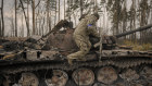 A Ukrainian serviceman jumps off a destroyed Russian tank outside Kyiv on Thursday.