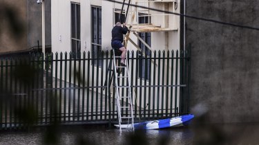 A man uses a canoe and ladder to access a property in Windsor as heavy flooding continues to impact the area.