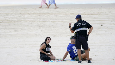 A police officer speaks with sunbathers on Surfers Paradise Beach at the Gold Coast.