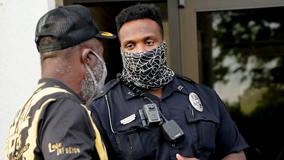 A citizen speaks with an officer in front of the municipal building after a deputy shot and killed a black man while executing a search warrant in North Carolina on Thursday (AEST).