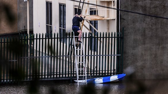A man uses a canoe and ladder to access a property in Windsor as heavy flooding continues to impact the area.