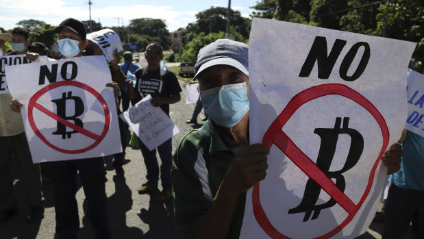 Farmers hold signs emblazoned with messages against the country adopting bitcoin as legal tender, during a protest along  the Pan-American Highway, in San Vicente, El Salvador.