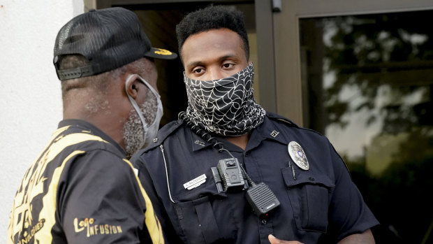 A citizen speaks with an officer in front of the municipal building after a deputy shot and killed a black man while executing a search warrant in North Carolina on Thursday (AEST).