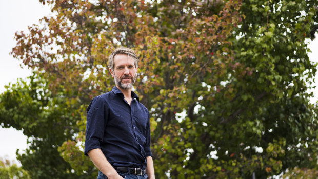 ANU lecturer of environmental measurement Matthew Brookhouse stands beside a flowering pear tree which is starting to change for autumn. 