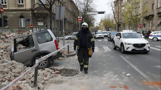 A firefighter inspects a car that was crushed by falling debris.