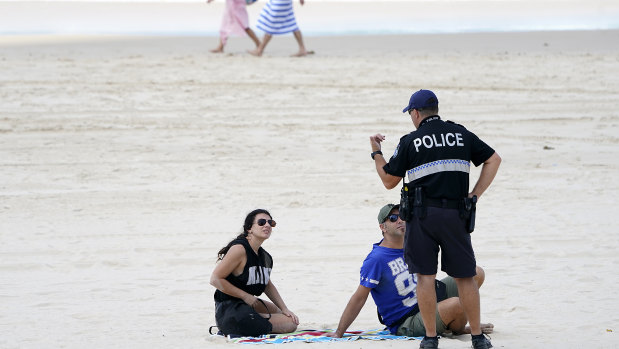 A police officer speaks with sunbathers on a Gold Coast beach in April.