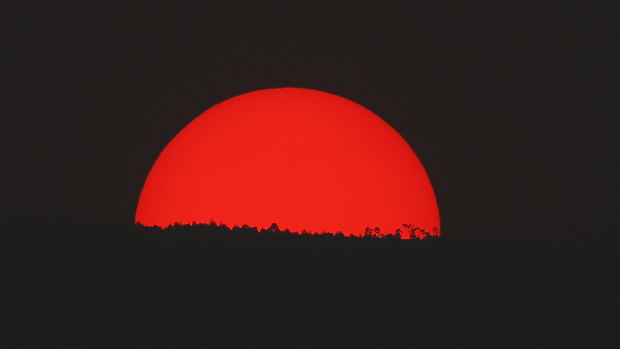 Tinted blood red by a thick cloud of smoke and pollution, the sun sets on the mountains above Mexico City on Monday.