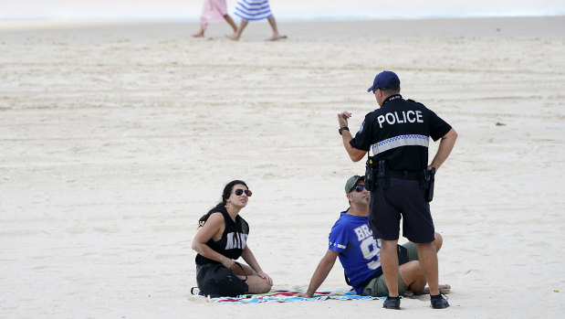 A police officer speaks with sunbathers on Surfers Paradise Beach at the Gold Coast.