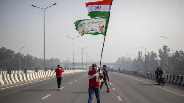 A protesting farmer waves an Indian flag and a farmer union flag as he marches with others to the capital breaking police barricades during India’s Republic Day celebrations in New Delhi, India.