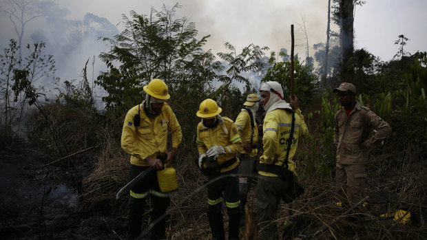 Firefighters rest briefly as they put out fires along the road to Jacunda National Forest.