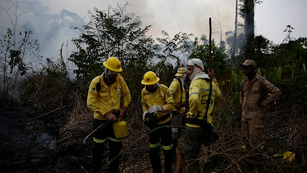 Firefighters rest briefly as they put out fires along the road to Jacunda National Forest.