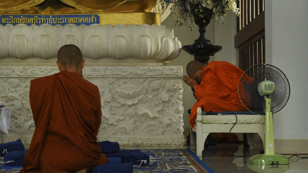 Dhammananda in prayer in front of a blue Buddha at the Songdhammakalyani Monastery.