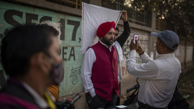 A roadside SIM card vendor takes a mugshot of a customer before selling a mobile connection to him near Delhi, India. 